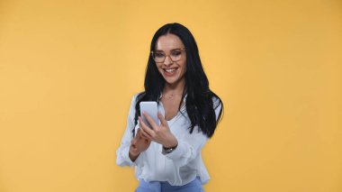 Genç, heyecanlı iş kadını cep telefonuyla mesajlaşması sarıda izole edilmiş.