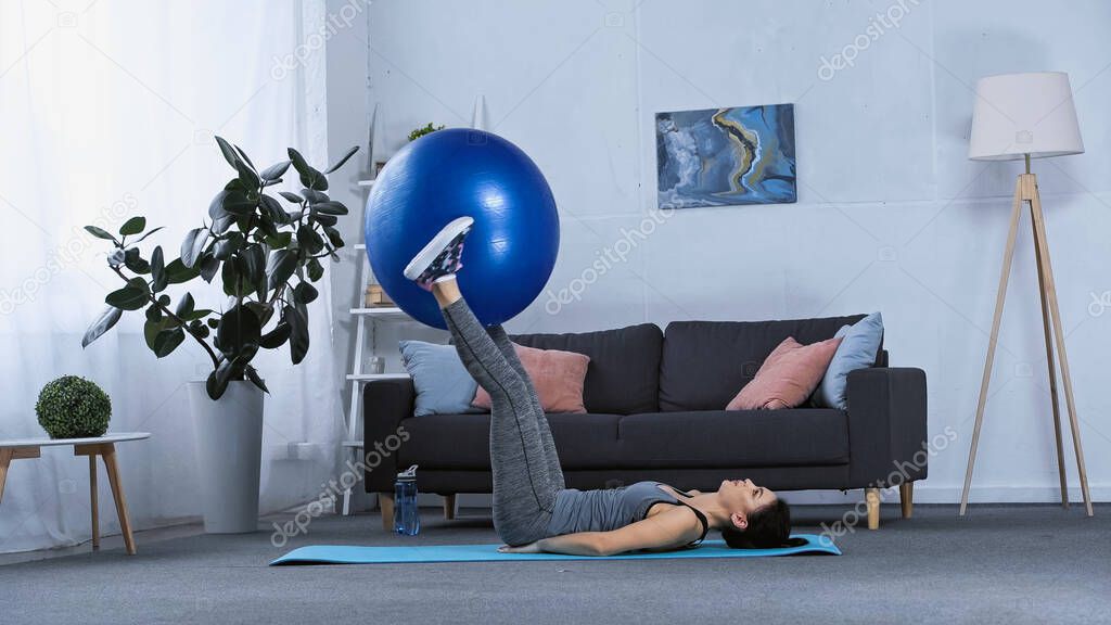 young brunette sportswoman exercising with fitness ball at home 