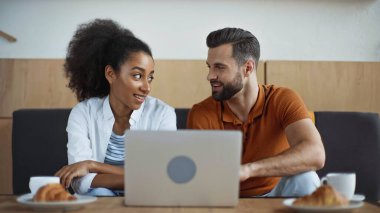 Kafede laptopun ve kahvaltının yanında birbirine bakan neşeli ırklar arası bağımsızlar.