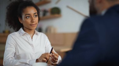 Afro-Amerikan iş kadını bulanık ön planda iş adamına bakıyor. 