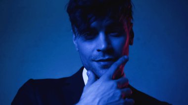 Ceketli adam mavi kameraya bakıyor.