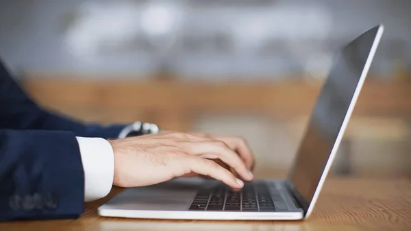 Laptop klavyesinde yazı yazan adamın kırpılmış görünümü 