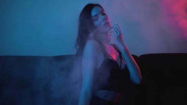 ブルーに煙でポーズをとるブルネットの女性に赤い照明 — ストック写真