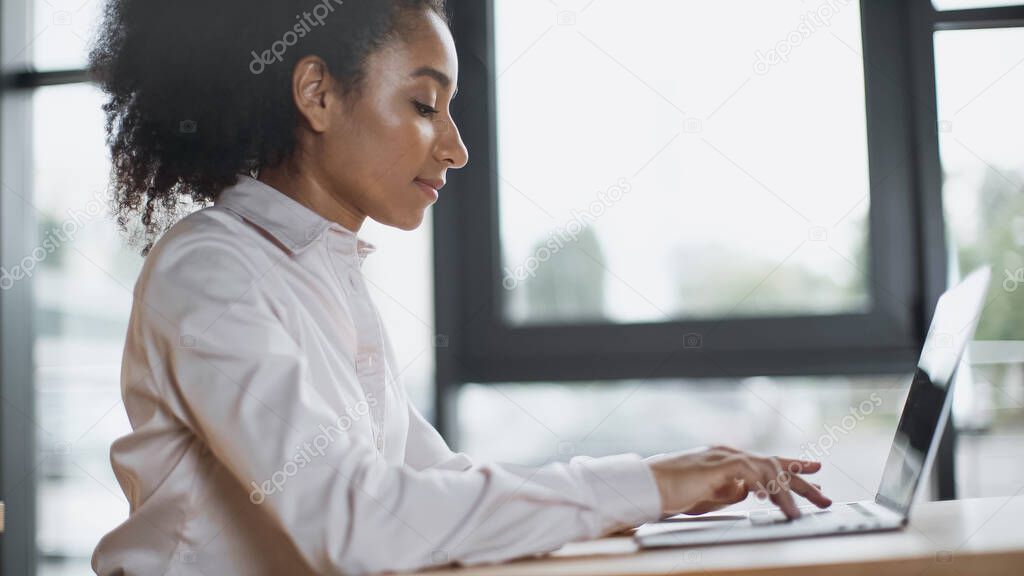 side view of african american woman typing on laptop keyboard 