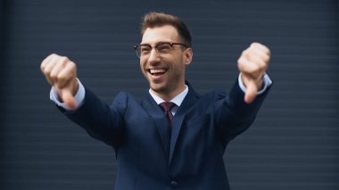 cheerful businessman in glasses showing thumbs down  clipart