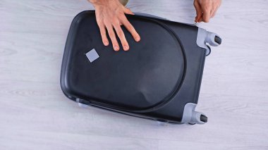 top view of man zipping black luggage  clipart