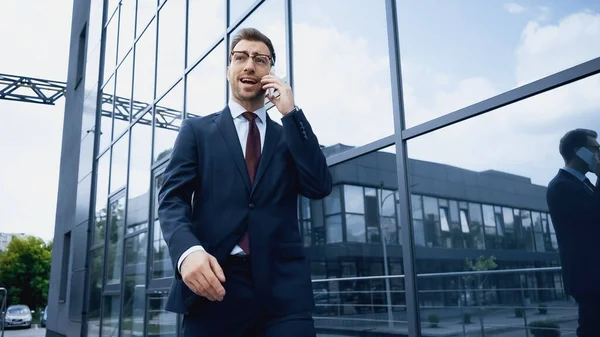 Hombre Negocios Gafas Traje Hablando Teléfono Inteligente Mientras Camina Cerca — Foto de Stock