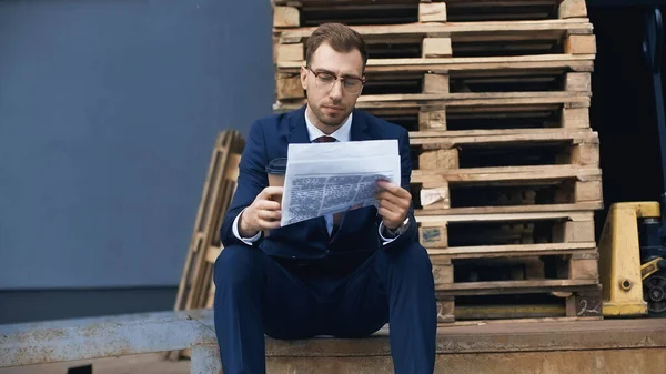 Empresário Sentado Enquanto Segurando Café Para Ler Jornal Fora — Fotografia de Stock