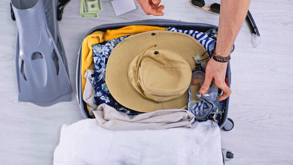 top view of man putting swimming mask while packing luggage 