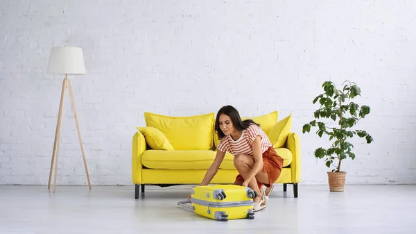 Brunette Woman Smiling While Looking Yellow Luggage Home — Stock Photo, Image