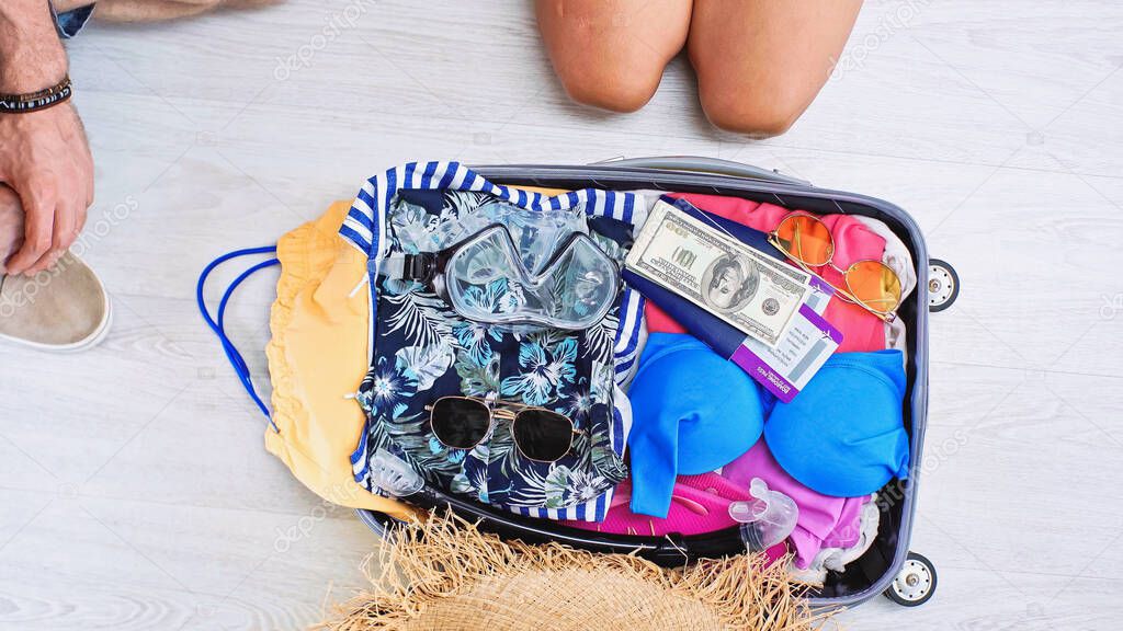 partial view of man and woman near baggage with summer clothes, money, passports and travel tickets 