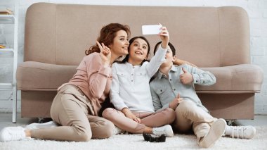 KYIV, UKRAINE - 15 Nisan 2019: Gülümseyen kadın, çocukların sevinç çubuğunun yanında selfie çekerken barış işareti gösteriyor 