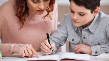 Defterde yazan çocuk, annesini işaret ederek evi işaret ediyor. 