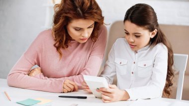 Annemin yanında ödev yaparken elinde hesap makinesi tutan kız. 