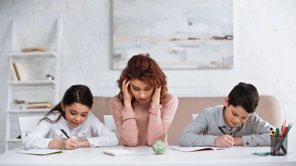 Frau Sitzt Neben Kindern Und Schreibt Bei Hausaufgaben Notizbüchern — Stockfoto