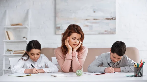 Mulher Sentada Perto Crianças Escrevendo Cadernos Durante Educação Casa — Fotografia de Stock