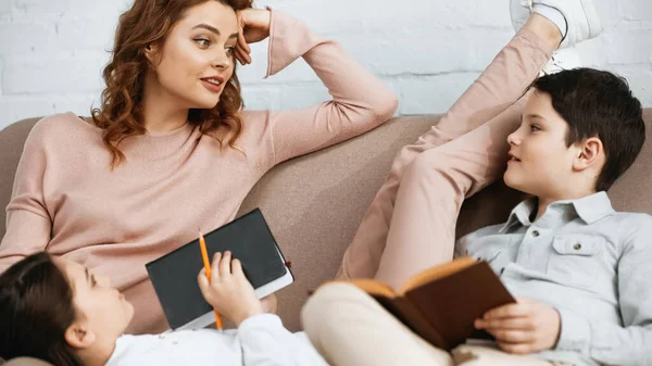 Mujer Sonriente Sentada Cerca Hija Hijo Con Cuaderno Libro Sofá — Foto de Stock