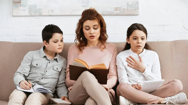 Niños Con Tablet Digital Notebook Sentados Cerca Madre Leyendo Libro — Foto de Stock