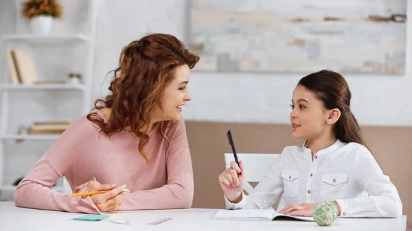 Sonriente Madre Apoyando Hija Con Tarea Mesa — Foto de Stock