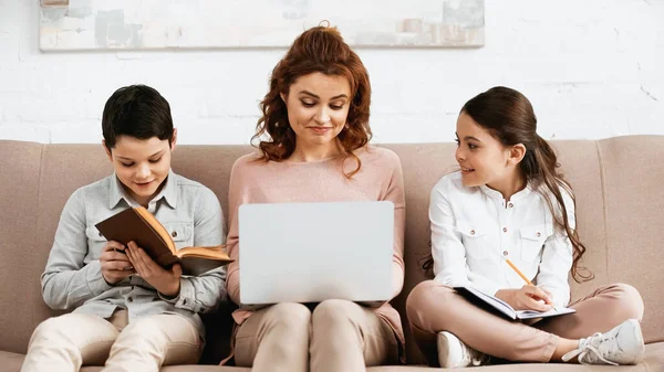 Leende Barn Gör Läxor Nära Mamma Med Laptop Soffan — Stockfoto