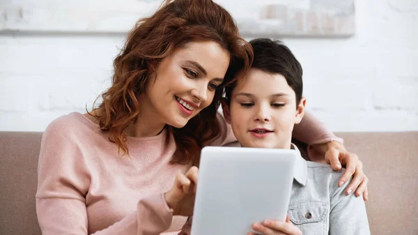 Lachende Moeder Met Digitale Tablet Wazige Voorgrond Buurt Van Zoon — Stockfoto