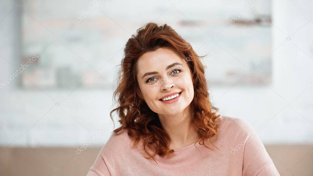 Red haired woman smiling at camera at home 