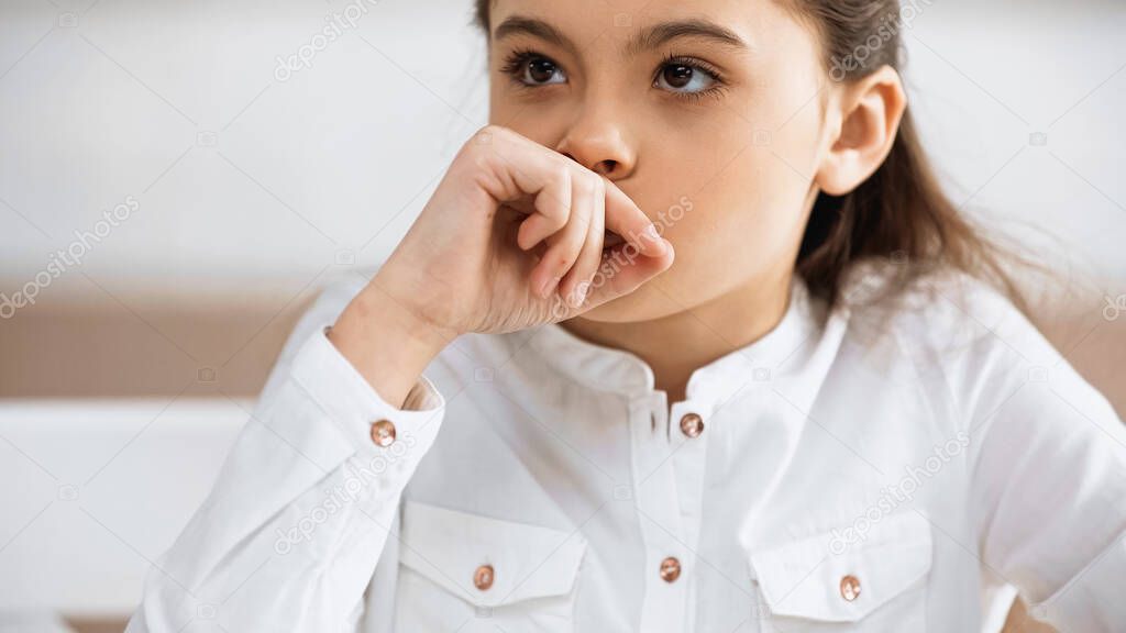 Pensive child in white shirt looking away 