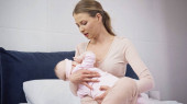 Frau hält Baby im Arm und stillt es zu Hause