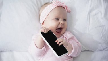 Heyecanlı bir bebeğin elinde boş ekranlı akıllı telefonu tutmasının en üst görüntüsü 