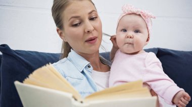 Çekici anne kız bebeğe kitap okuyor.