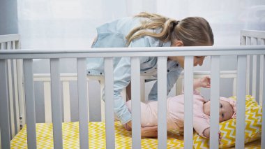 Mutlu anne bebeğini beşiğine koyuyor. 