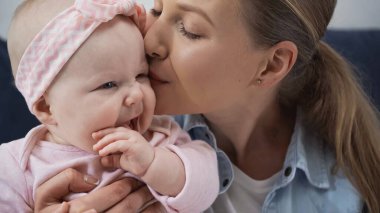 caring mother kissing cheek of baby daughter  clipart