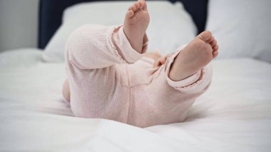 cropped view of barefoot baby lying on bed clipart
