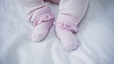 cropped view of baby in romper and socks in bed clipart