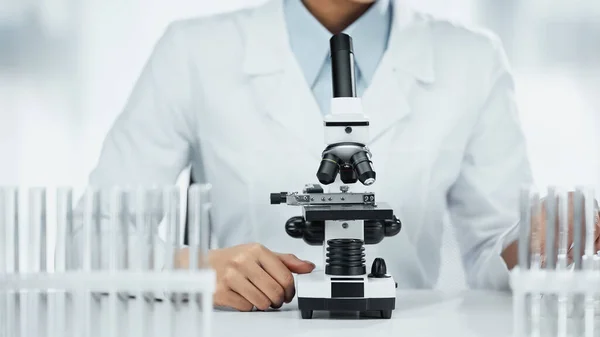 stock image cropped view of african american scientist near microscope and test tubes in lab 