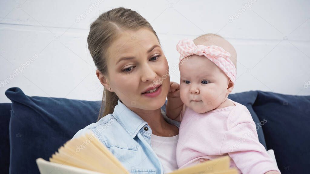 attractive mother reading book to infant baby girl