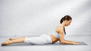 Sfenks yoga pozu veren çıplak ayaklı kadın.