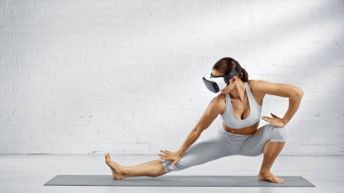 VR kulaklıklı kadın yoga minderinde geriniyor. 