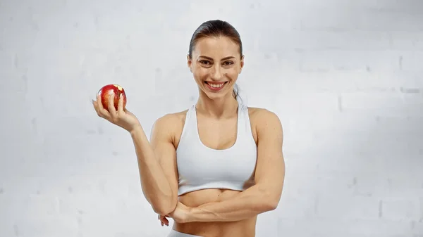 积极的女运动员拿着苹果 看着镜头 — 图库照片