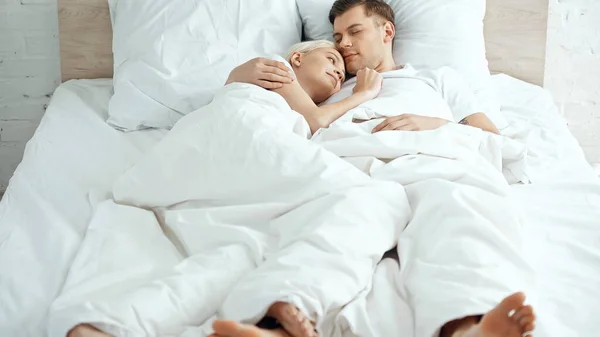 光着脚的夫妻躺在床上的毛毯下 — 图库照片