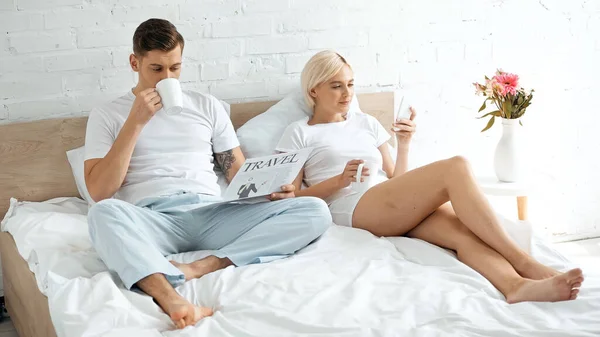 Tattooed Man Reading Travel Newspaper Drinking Coffee Woman Using Smartphone — Stock Photo, Image