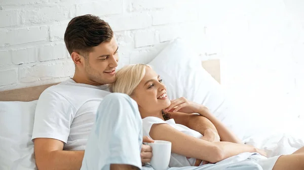 Tattooed Man Holding Cup Coffee Cheerful Woman Lying Bed — Stock Photo, Image