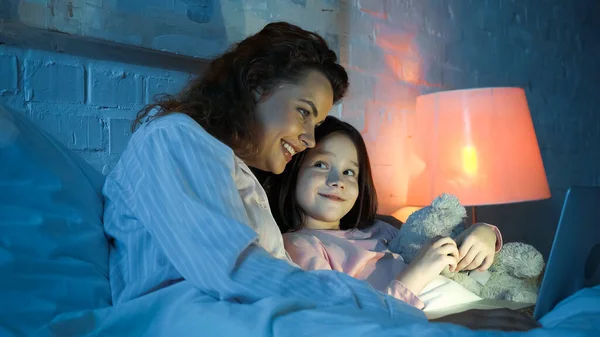 Smiling Child Teddy Bear Looking Mother Using Laptop Bed — Stock Photo, Image