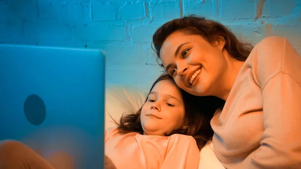 幸せな女性と娘見ますぼやけたラップトップでベッドルーム — ストック写真