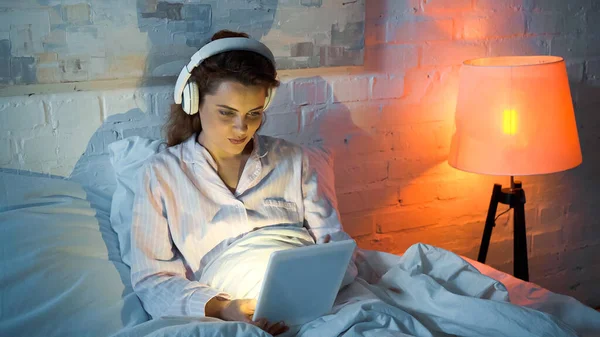 Vrouw Hoofdtelefoon Met Behulp Van Digitale Tablet Bed Tijdens Avond — Stockfoto