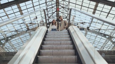 low angle view of couple near escalator in shopping mall  clipart