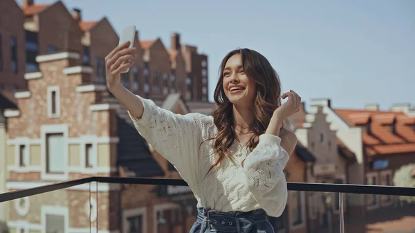 Feliz Joven Mujer Tomando Selfie Cerca Edificios Borrosos — Foto de Stock