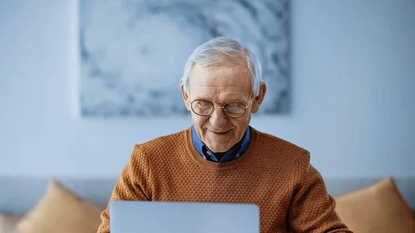 Uśmiechnięty Staruszek Pracujący Laptopie Nowoczesnym Salonie — Zdjęcie stockowe