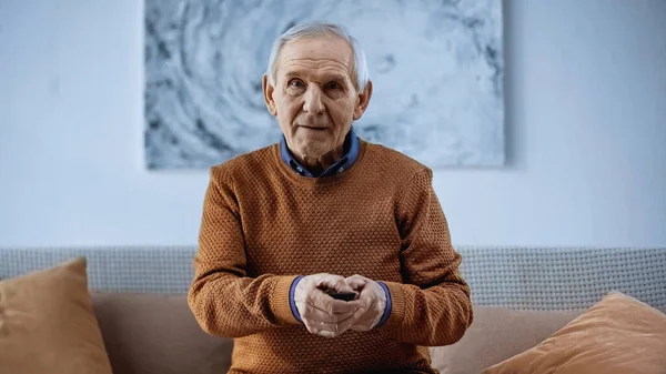 Uomo Anziano Seduto Sul Divano Con Telecomando Guardando Fotocamera Casa — Foto Stock