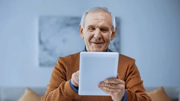 Gülümseyen Yaşlı Adam Modern Oturma Odasında Tablet Kullanıyor — Stok fotoğraf
